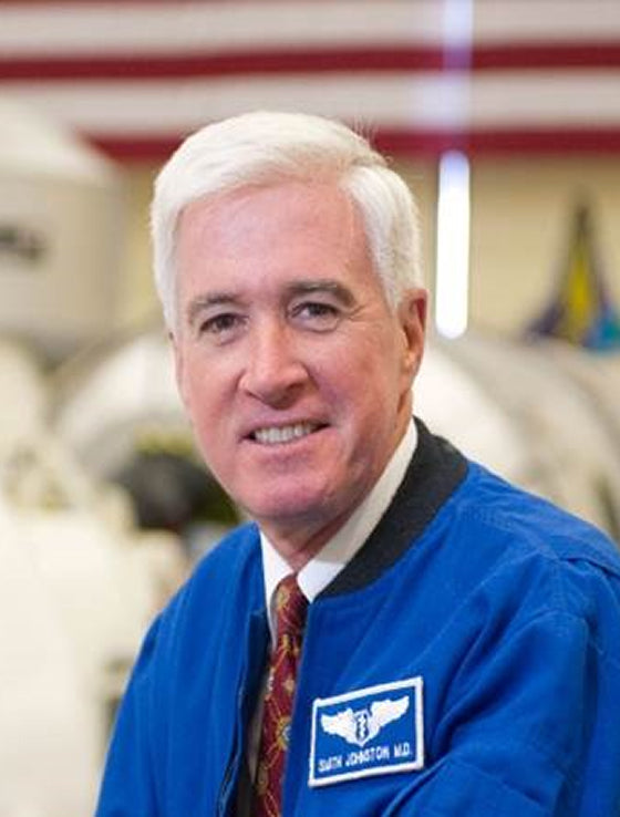 Man wearing a blue jacket with a logo in an indoor setting